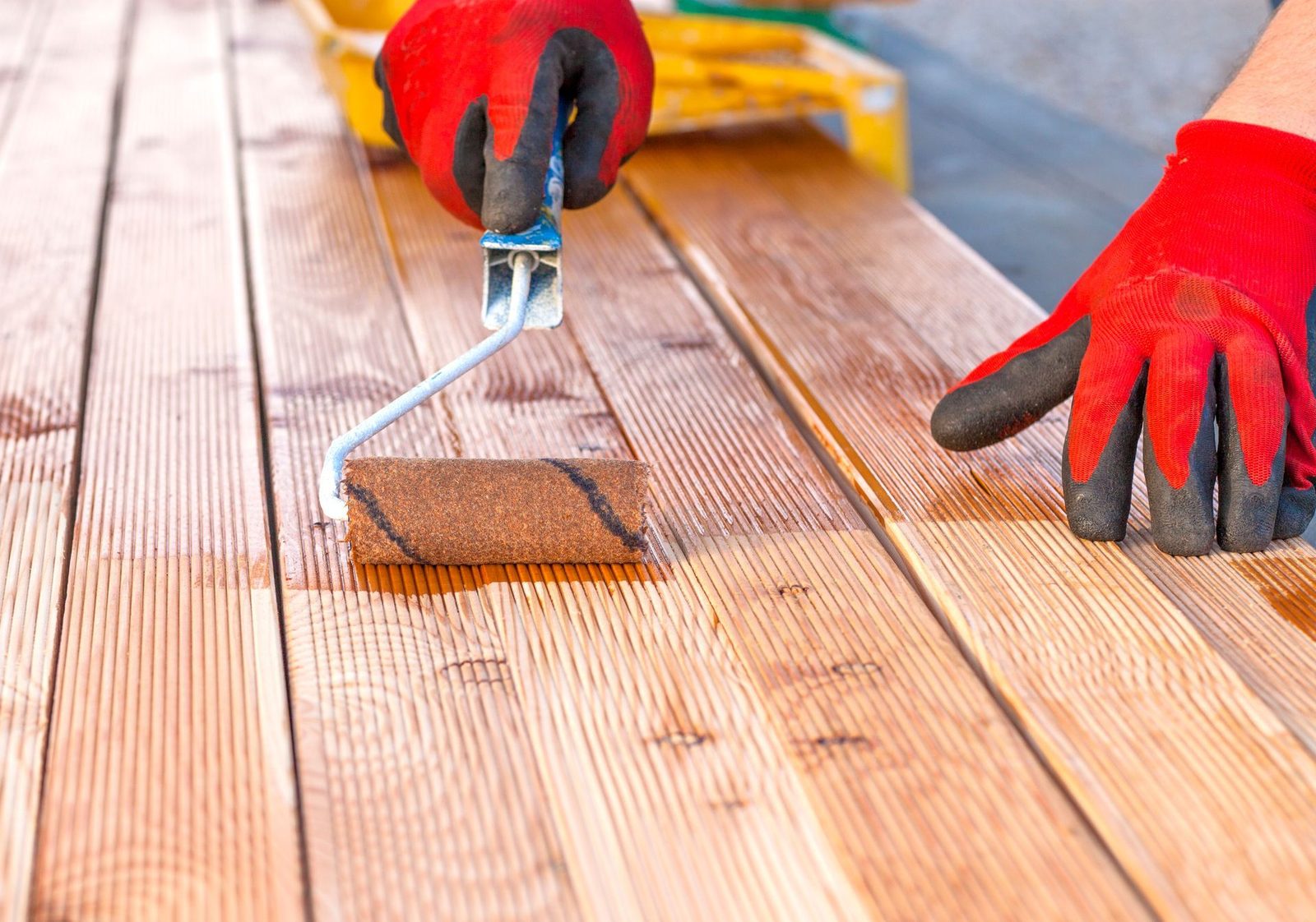Painter applying a protective finish to an outdoor deck