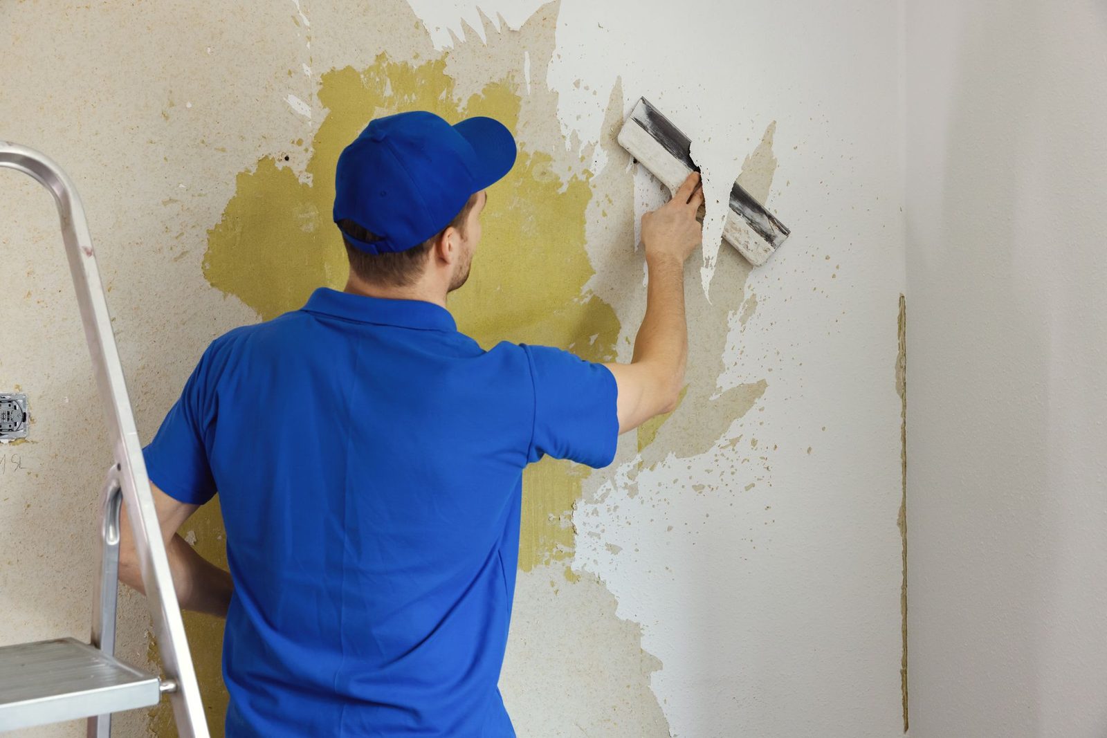 Wallpaper being carefully removed from an interior wall